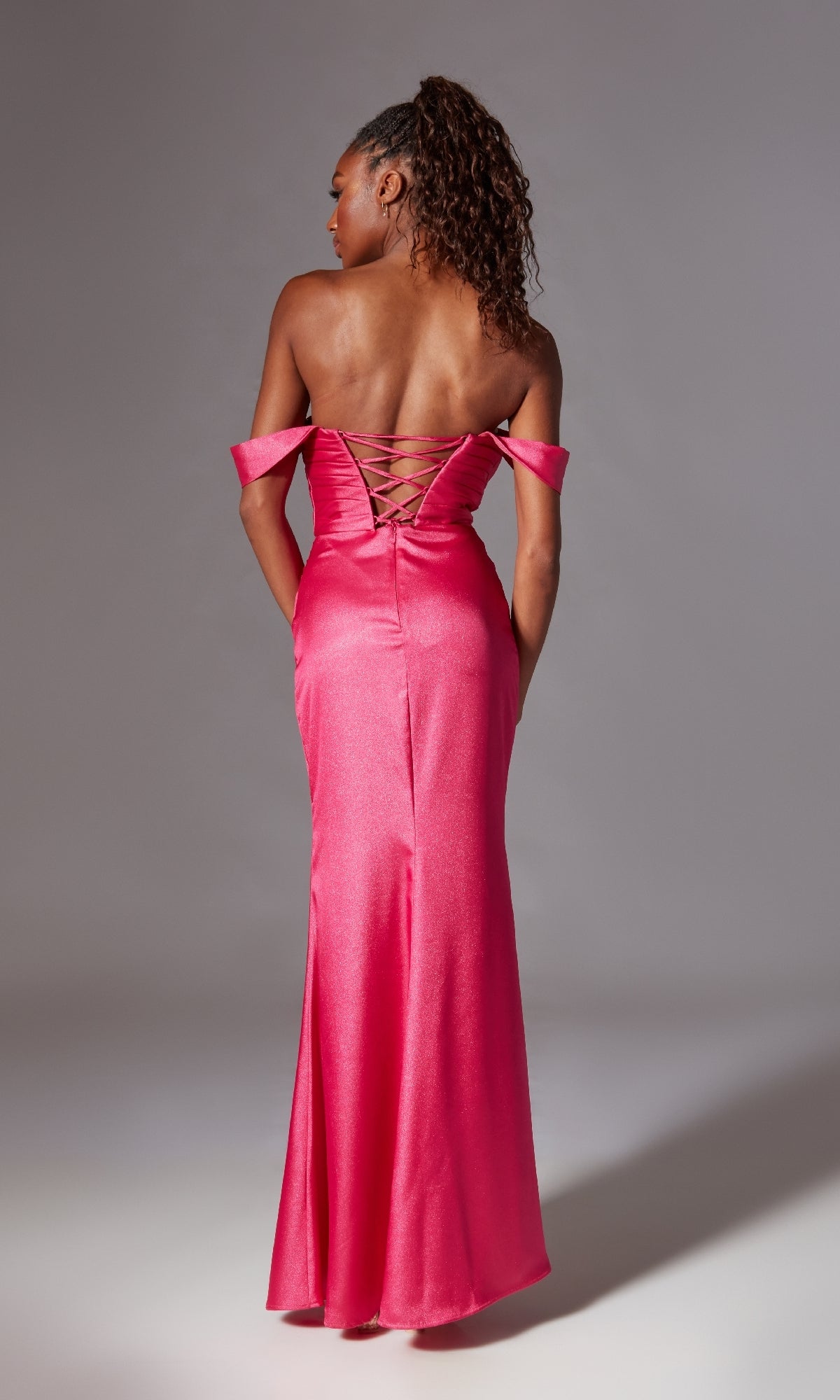 A woman faces away, wearing the Long Shimmer Prom Dress: Aerie Couture 211—featuring an off-the-shoulder neckline, lace-up open back, and a floor-length skirt.